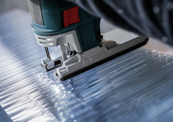 沿直線用拼圖鋸切割透明丙烯酸板。.