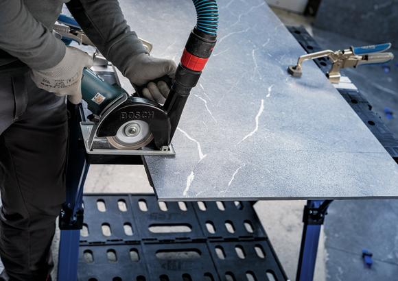 配戴安全設備的人員用電鋸切割石板。.