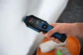 一個人將材料濕度計壓在白牆上。
