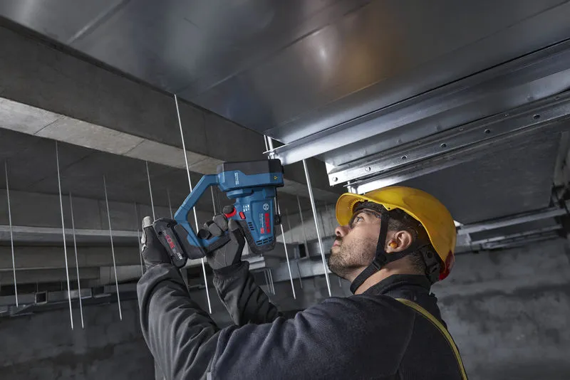 一名配戴安全設備的人員使用無線螺紋桿切割器切割天花板桿。.