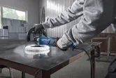配戴安全設備的人在金屬工作台上使用拋光機。.