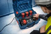 一名配戴安全設備的人員在工作現場操作多電池充電站。.