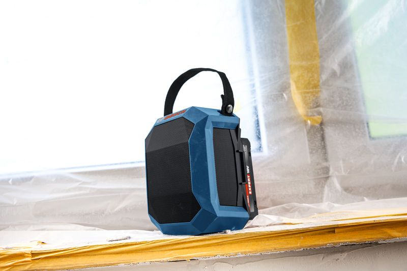 帶有提把的藍色藍牙揚聲器放置在建築工地的窗台上。.