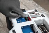 穿戴安全裝備的人員正在調整牆式採礦機的電池。