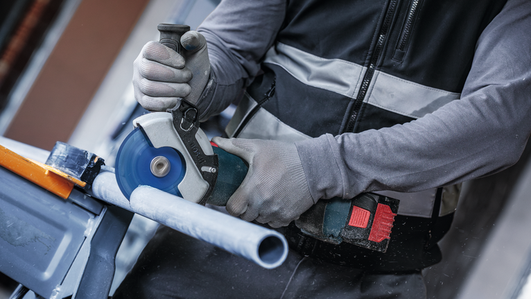 超耐久鎢鋼多功能切片 X-LOCK 切削砂輪片 125 mm,22.23 mm 配戴安全設備的人員用圓鋸切割塑膠管。