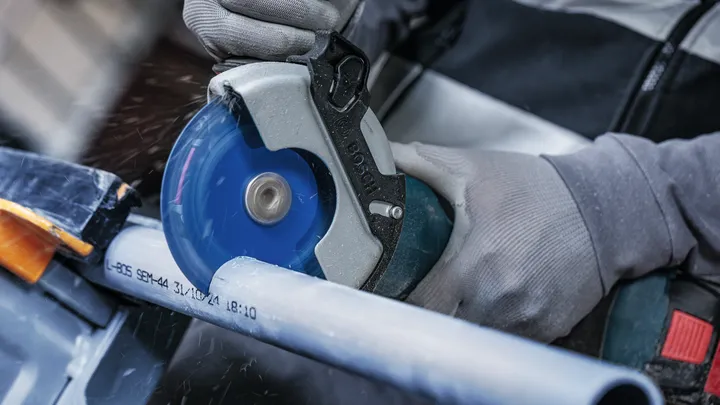 配戴安全設備的人員用圓鋸切割塑膠管。