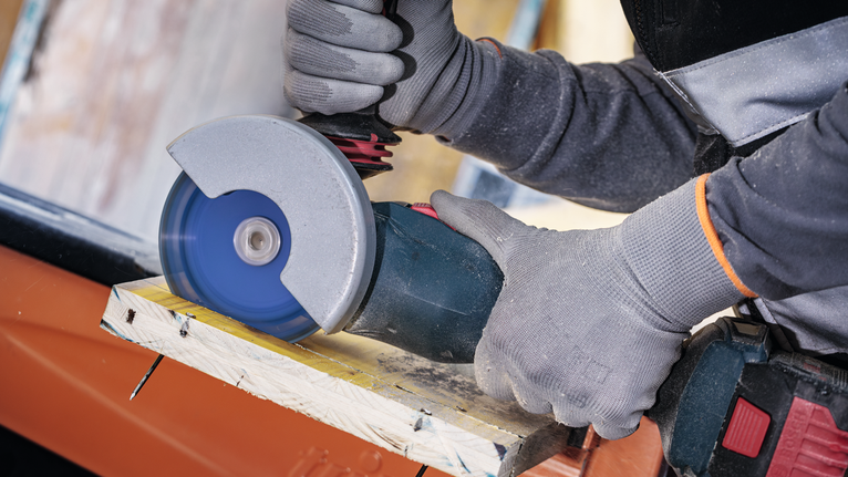 超耐久鎢鋼多功能切片 X-LOCK 切削砂輪片 125 mm,22.23 mm 配戴安全設備的人員使用角磨機切割木材。