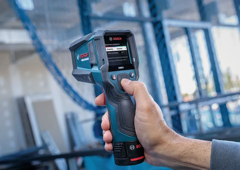 Person operating a thermo detector with a digital display at a construction site.