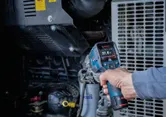Person uses a thermo detector to measure the temperature of machinery.