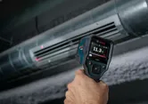 Person using a thermo detector to measure air temperature at an HVAC vent.