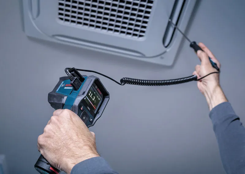 A person uses a thermo detector to measure temperature at an air vent.