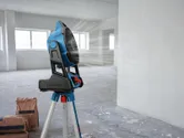 一台架在三腳架上的便攜式工地風扇，正對著一個擺放著建築垃圾袋的空房間吹風。