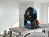 一台無線工地風扇正在一個剛粉刷過的房間裡的金屬工作平台上運作。